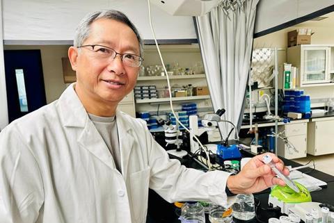 Prof Jie Zheng of UC Davis School of Medicine in a laboratory, holding a pipette beside scientific equipment.